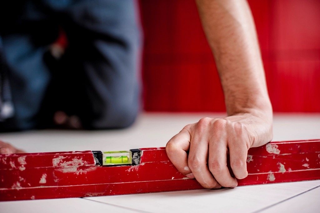 Hand op een rode waterpas op een lichte vloer